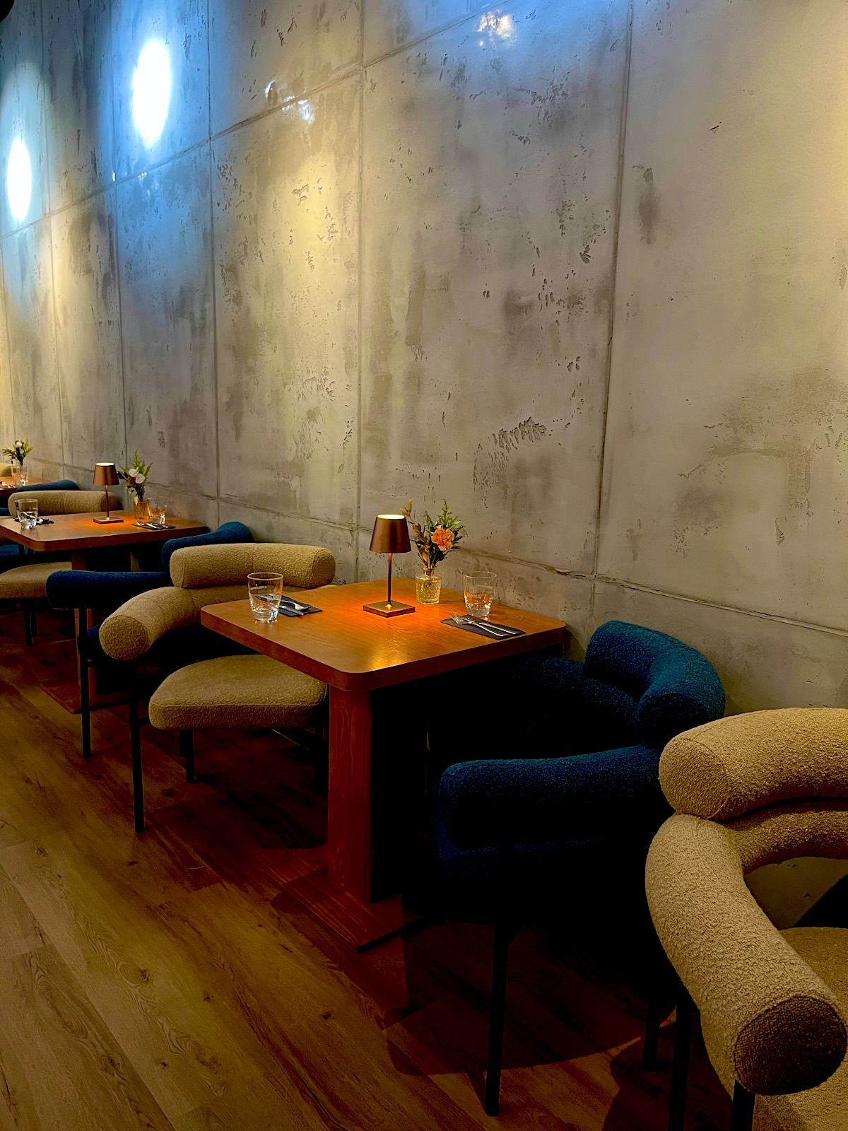Gastraum von SONO in Dortmund am Abend: Tisch mit Lampe und Bouclé-Sessel in Creme und Petrol